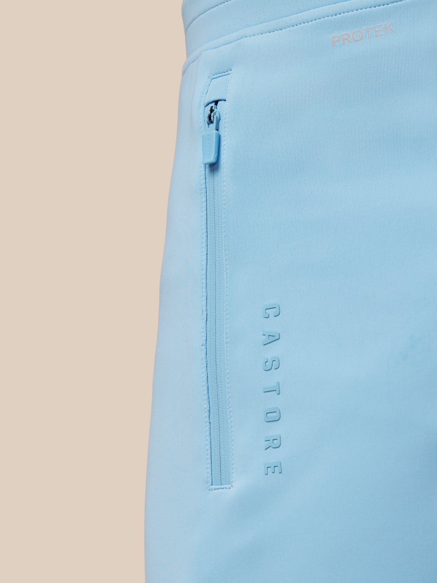 Light blue pants with 'Castore' branding on a beige background