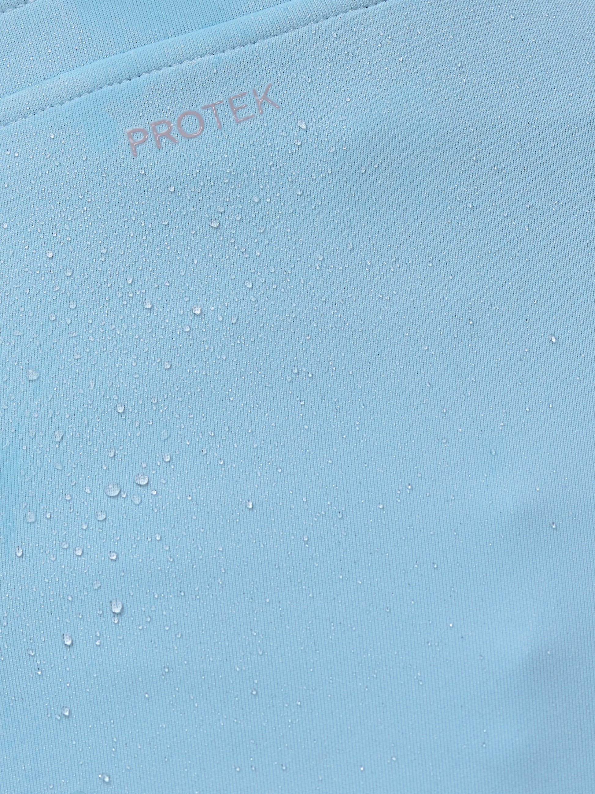 Close-up of a blue fabric with 'PROTEK' branding.