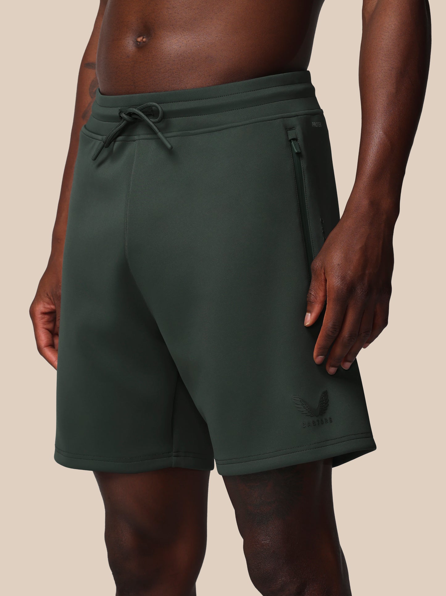 Dark green shorts worn by a person on a beige background