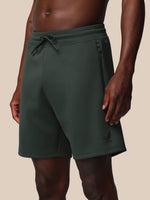 Dark green shorts worn by a person on a beige background