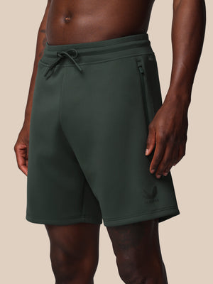Dark green shorts worn by a person on a beige background