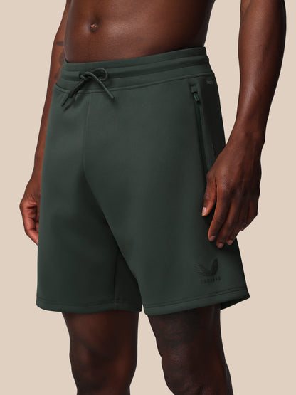 Dark green shorts worn by a person on a beige background