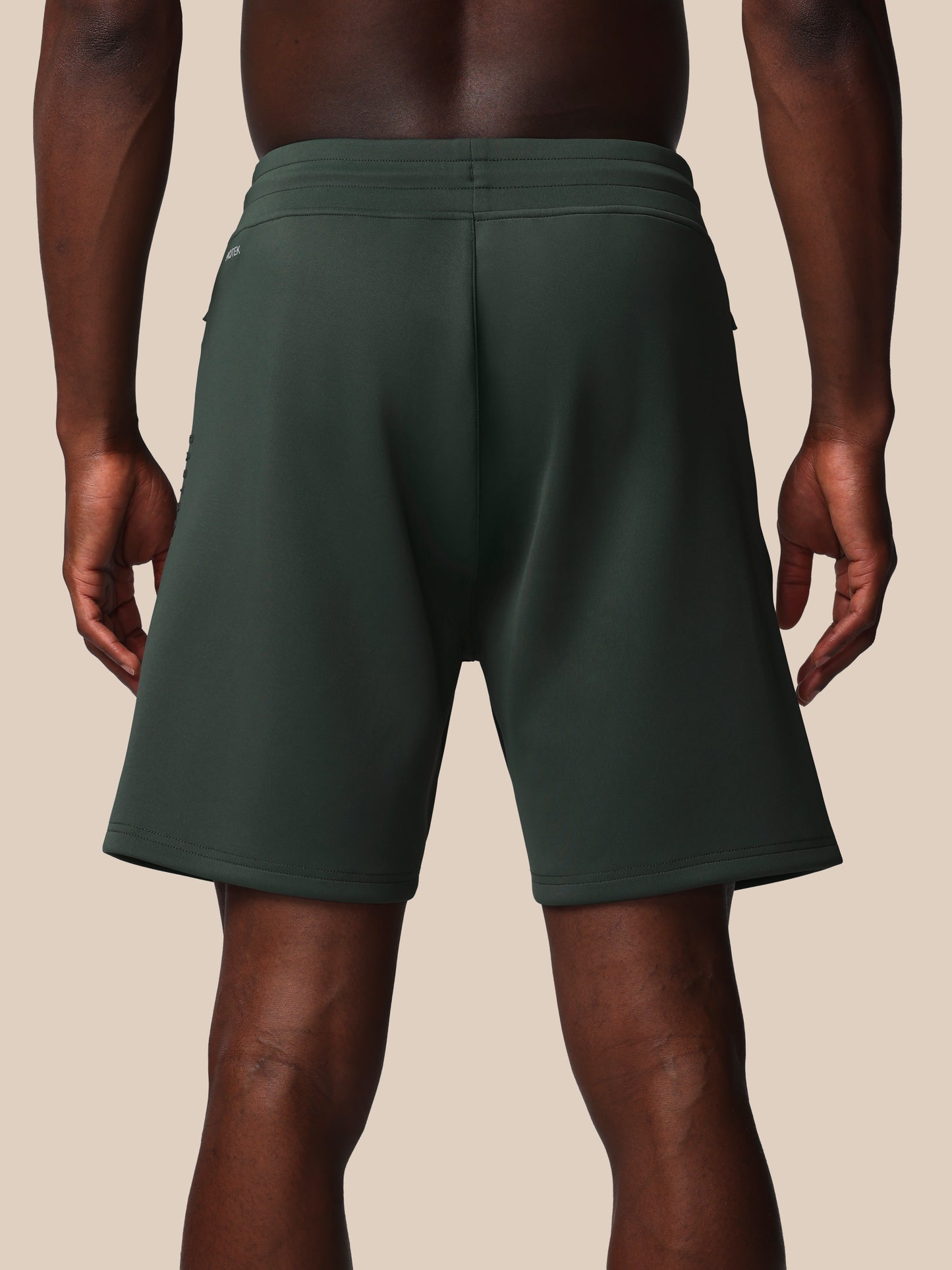 Person wearing dark green shorts on a beige background