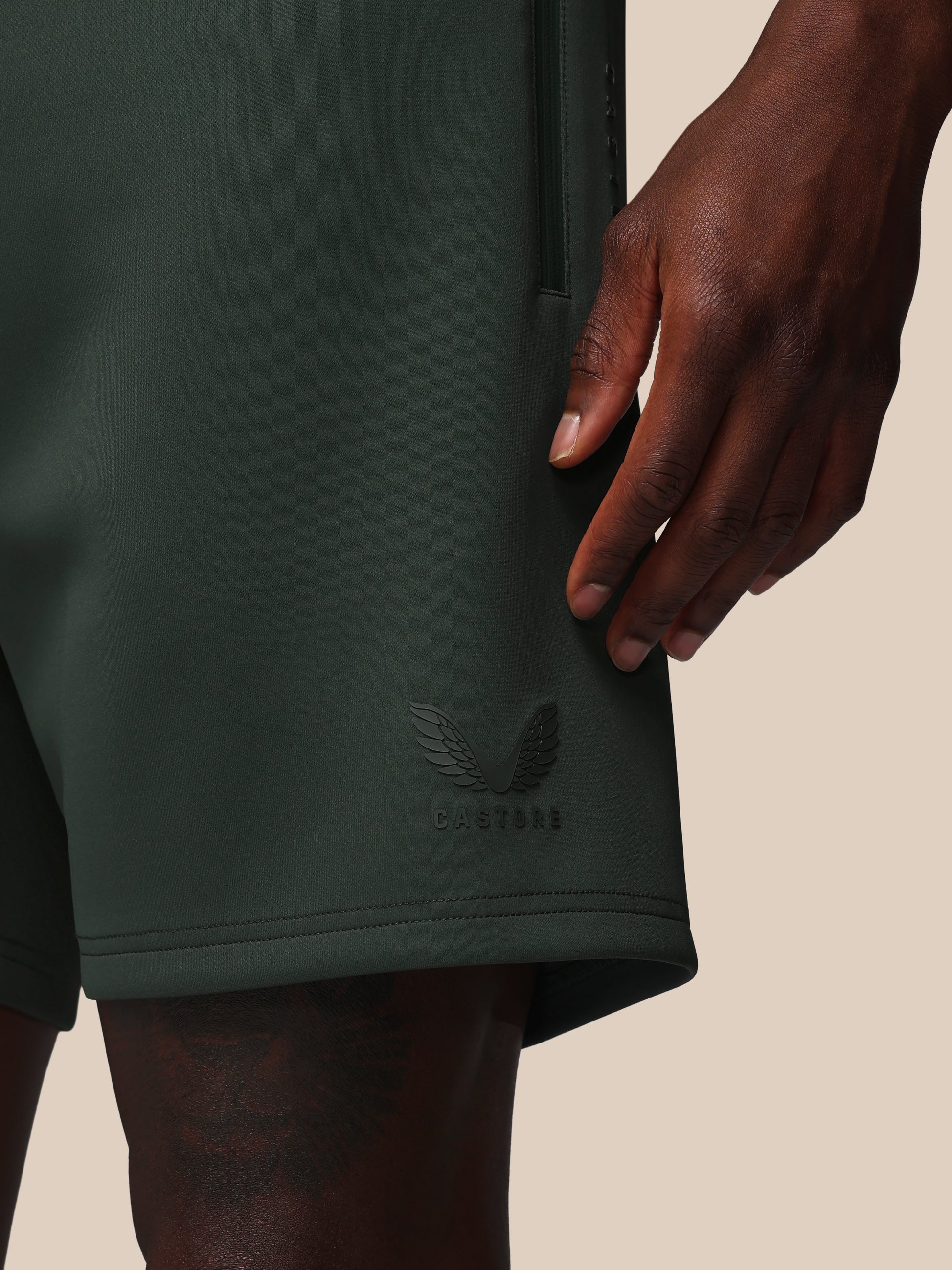 Dark green shorts with a brand logo on a beige background