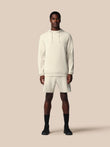 Man wearing a white hoodie and shorts set on a beige background