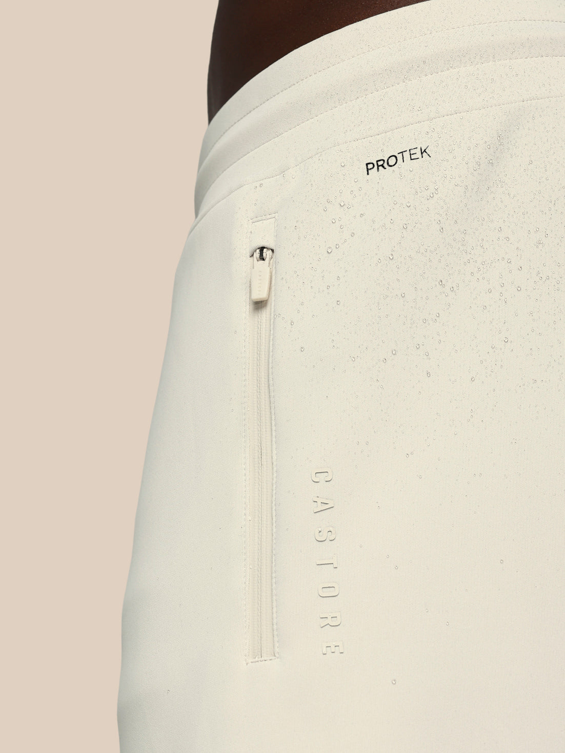 Light gray pants with a zipper and 'Protek' branding on a beige background
