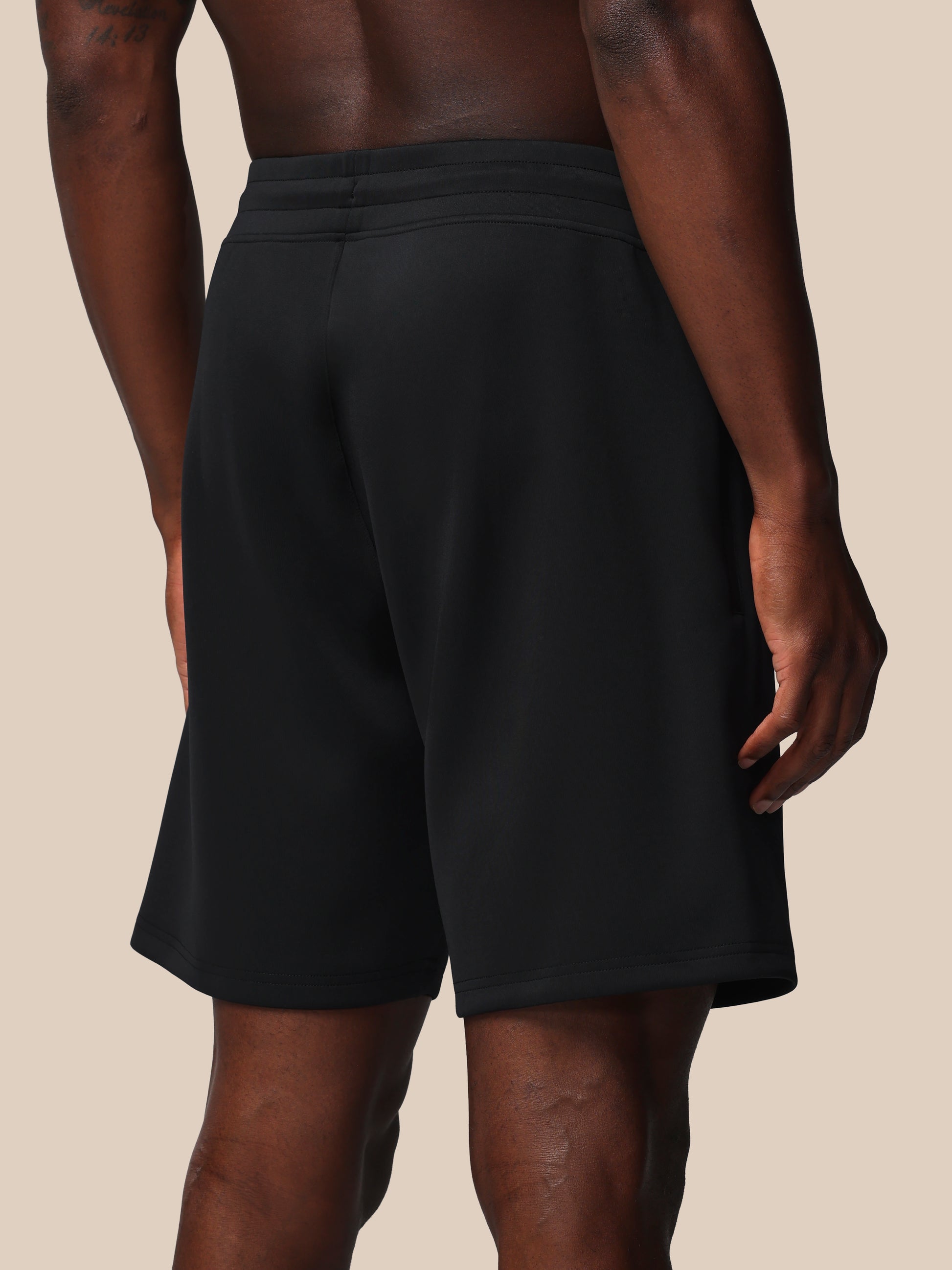 Person wearing black shorts on a beige background