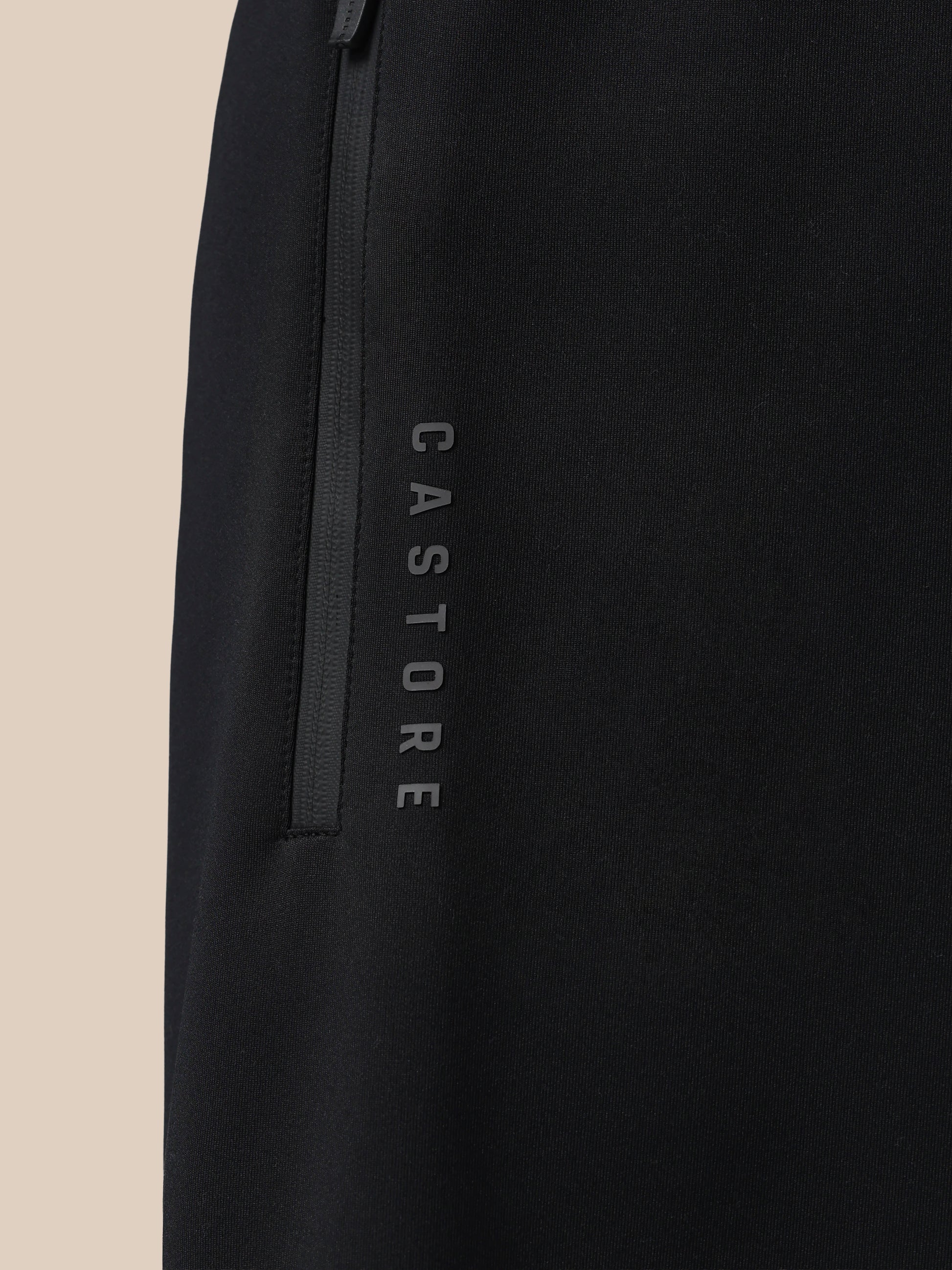 Black jacket with 'Castore' branding on a beige background