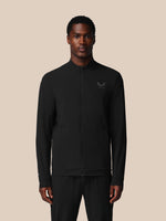 Man wearing a black jacket with a logo on a beige background