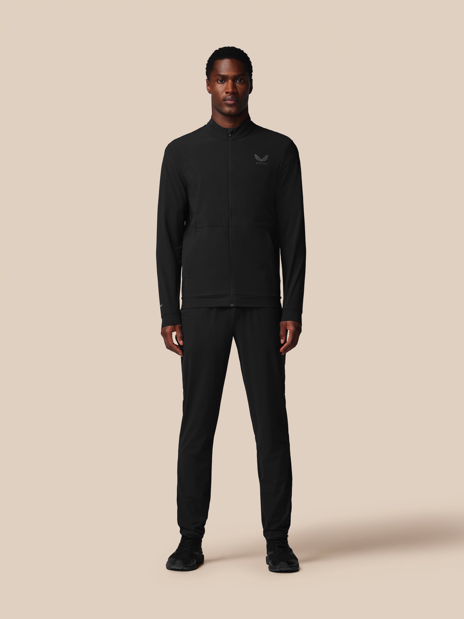 Man wearing a black long-sleeve shirt and pants on a beige background