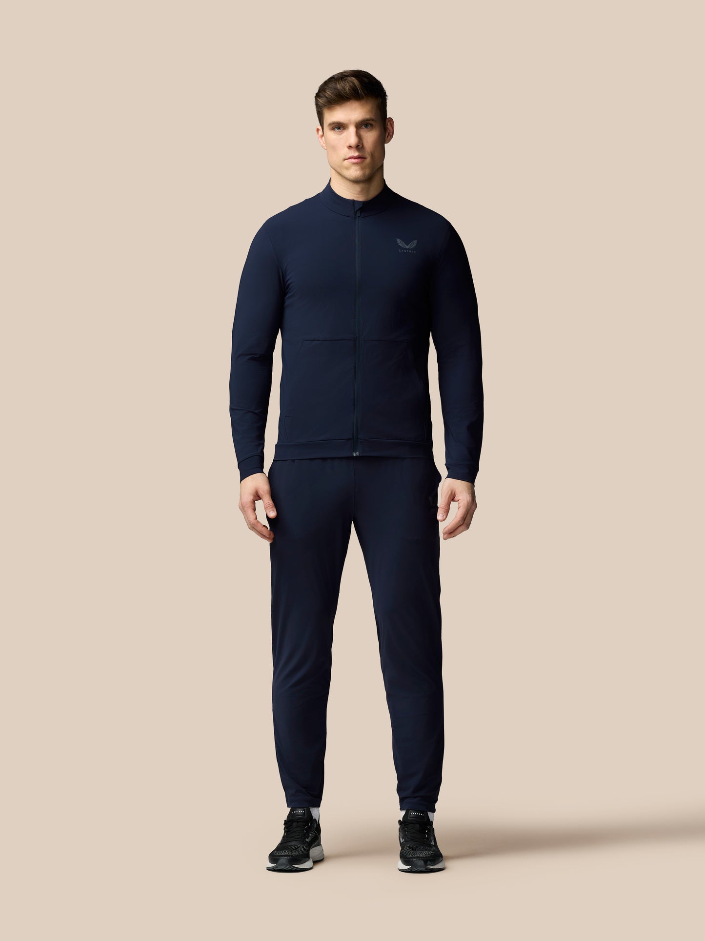 Man wearing a navy tracksuit on a beige background