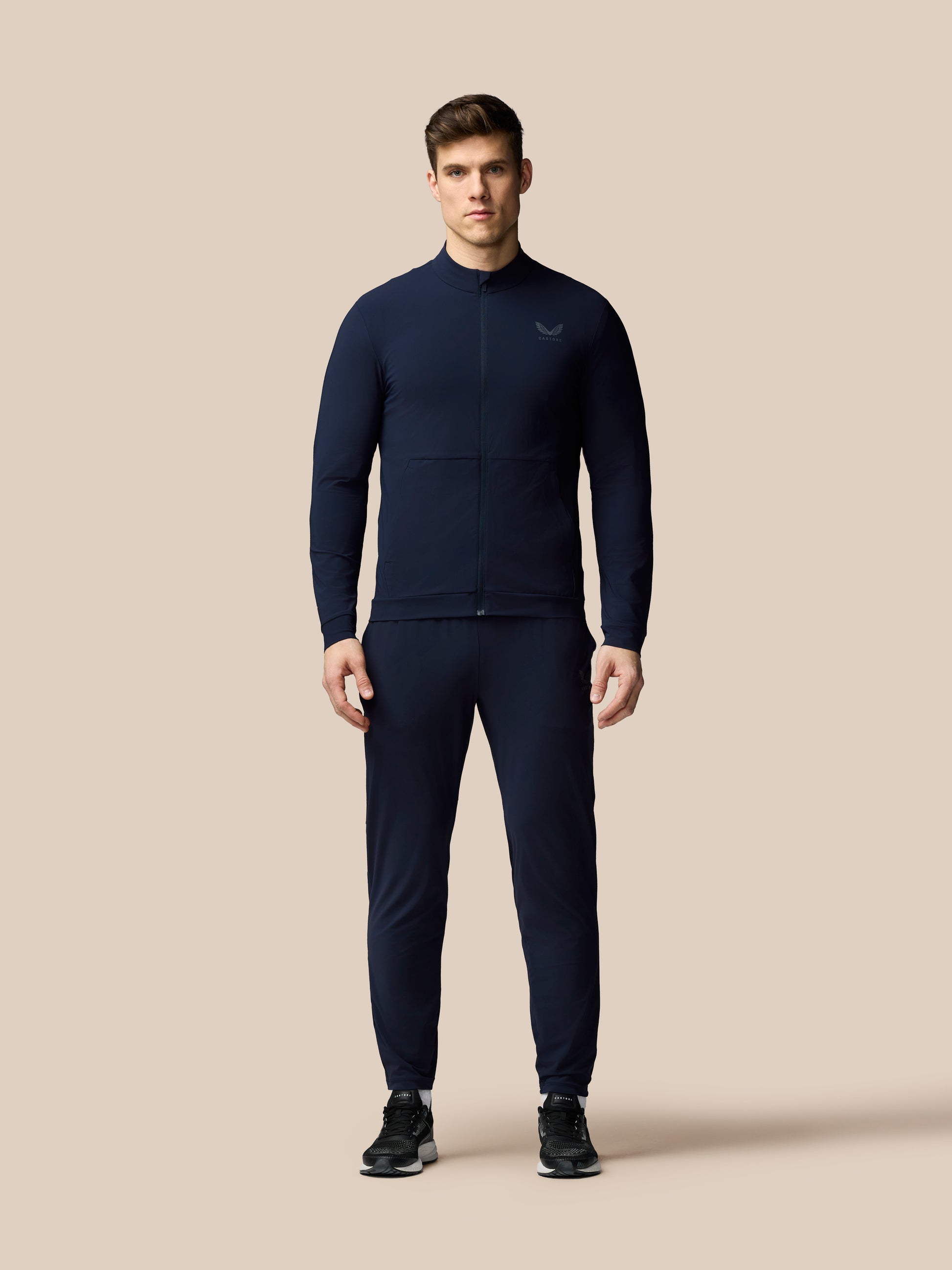 Man wearing a navy tracksuit on a beige background