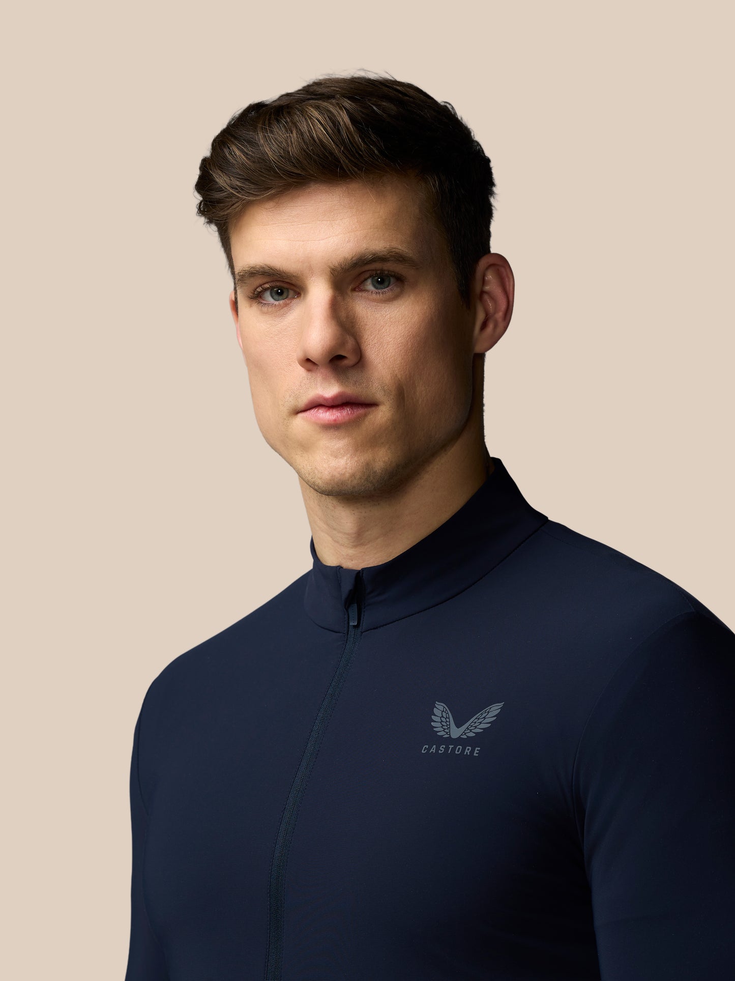 Man wearing a navy blue shirt with a logo on a beige background