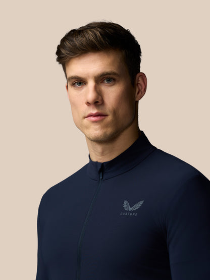 Man wearing a navy blue shirt with a logo on a beige background