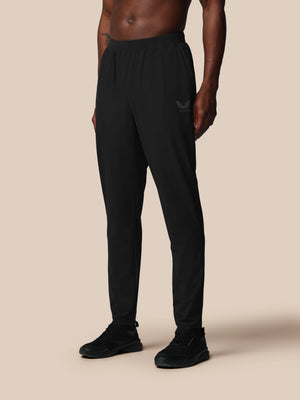Person wearing black Castore pants on a beige background