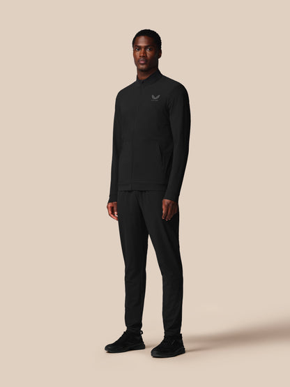 Man wearing a black outfit with a logo on a beige background
