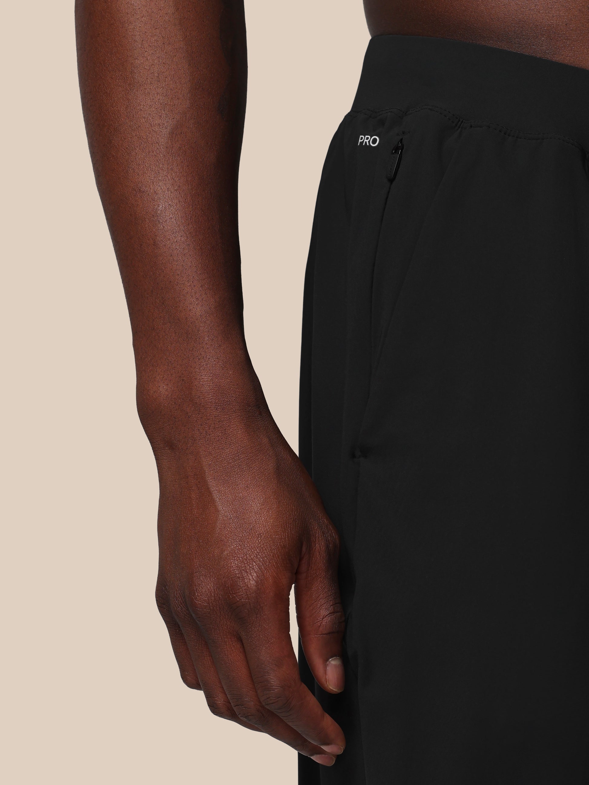 Person wearing black athletic pants with a visible brand logo on a beige background