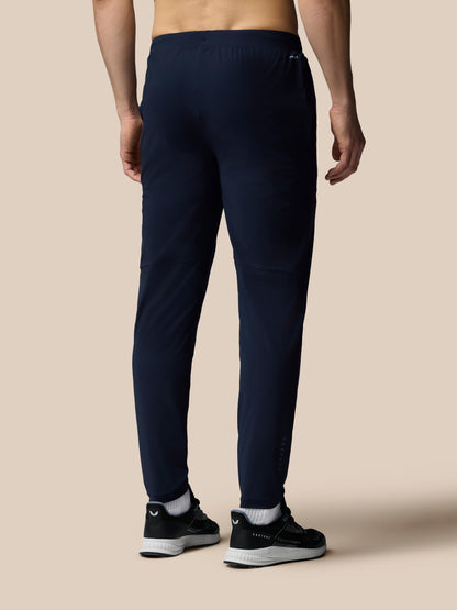 Person wearing navy jogger pants on a beige background