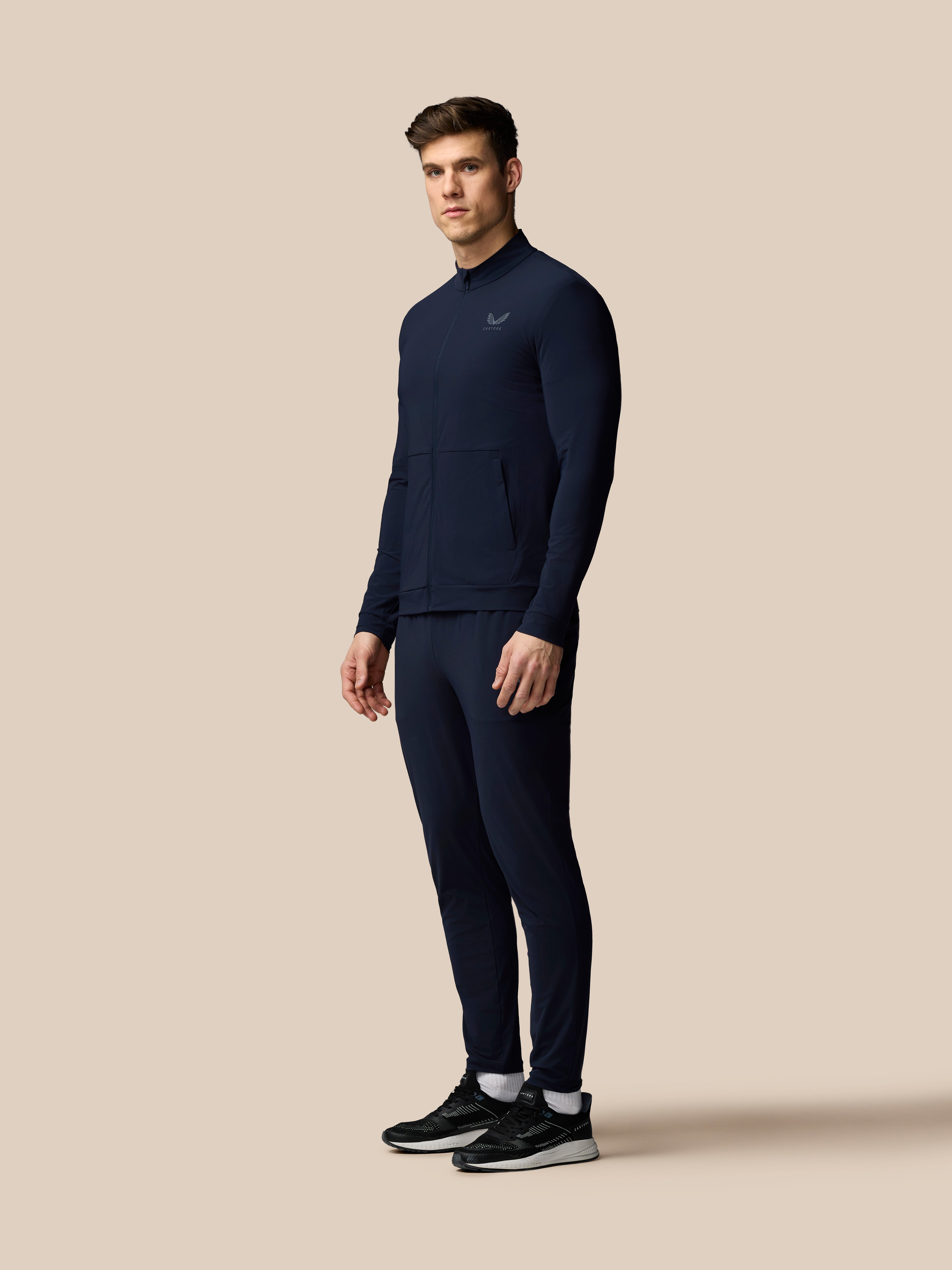 Man wearing a navy tracksuit on a beige background