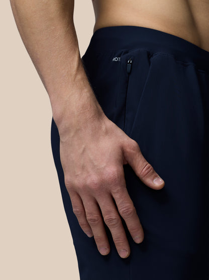 Person wearing dark blue pants with a beige background