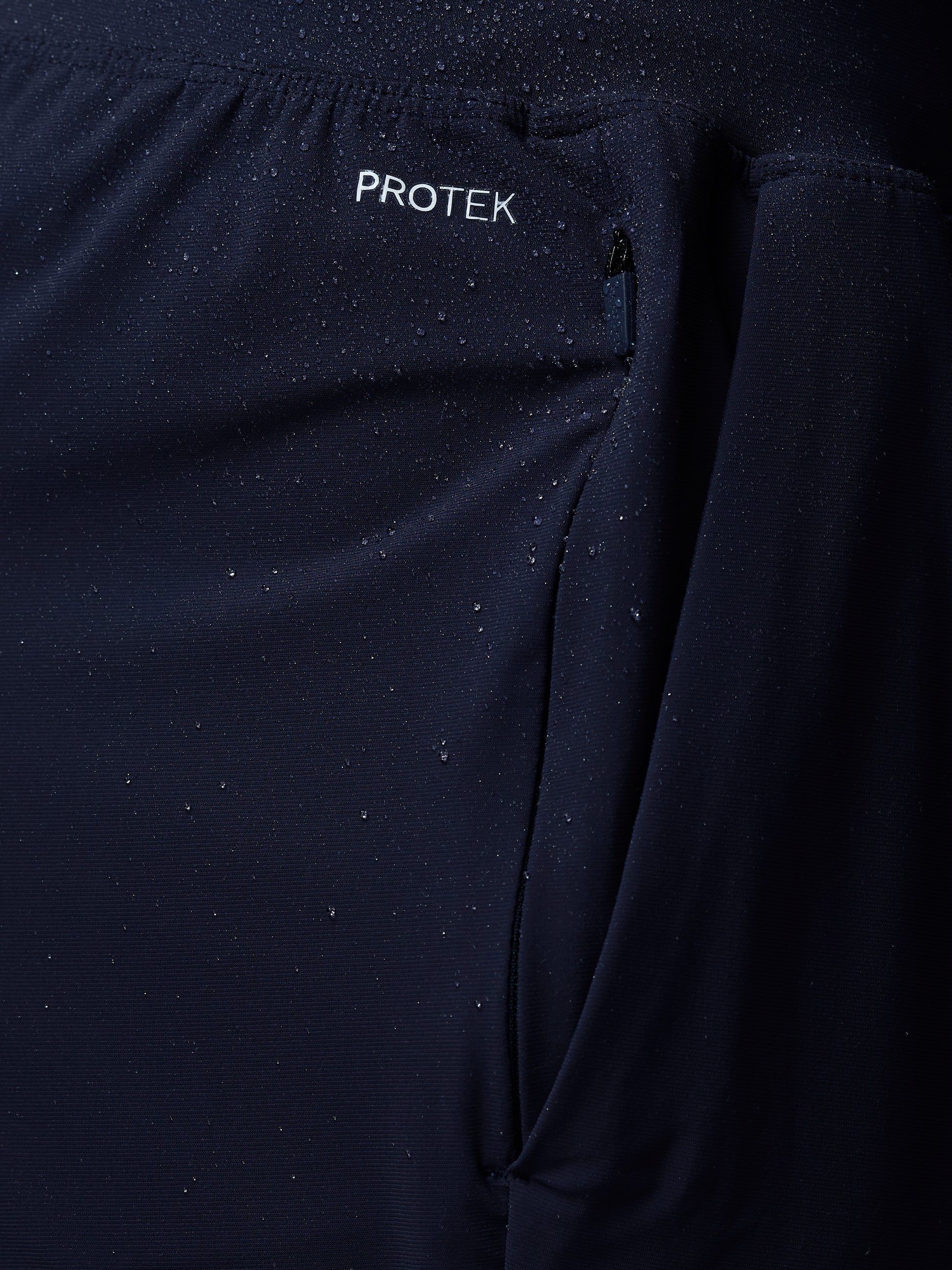 Close-up of a dark blue jacket with 'PROTEK' branding on a black background