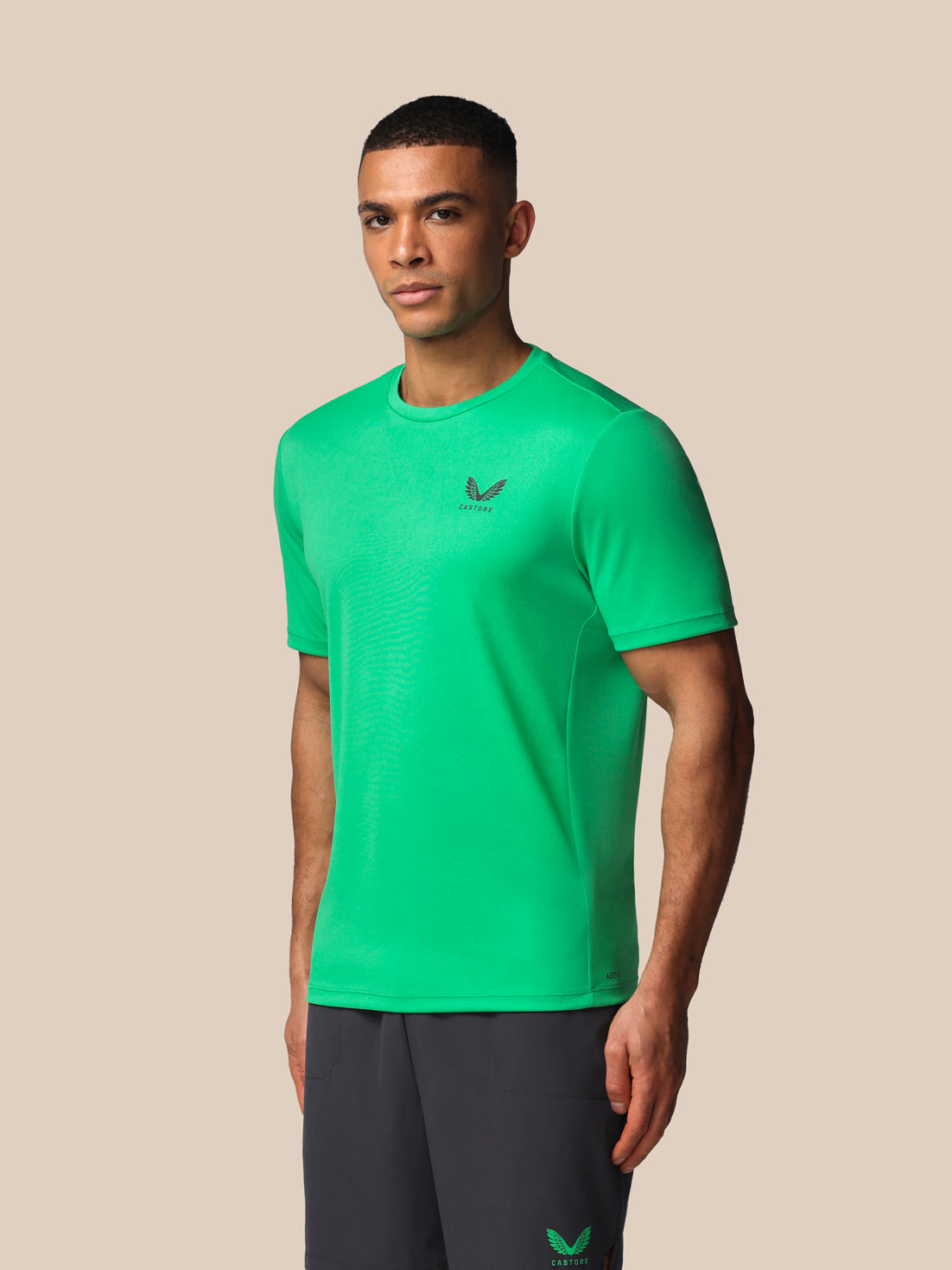 Man wearing a green athletic shirt with a logo on a beige background