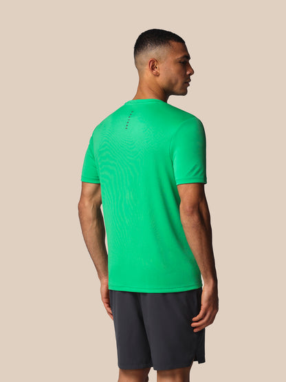Man wearing a green t-shirt and black shorts on a beige background