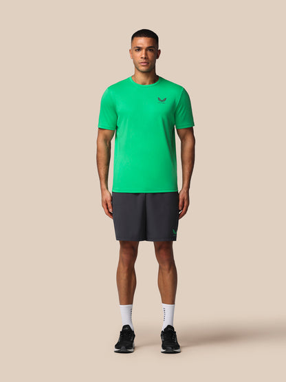 Man wearing a green athletic shirt and black shorts on a beige background