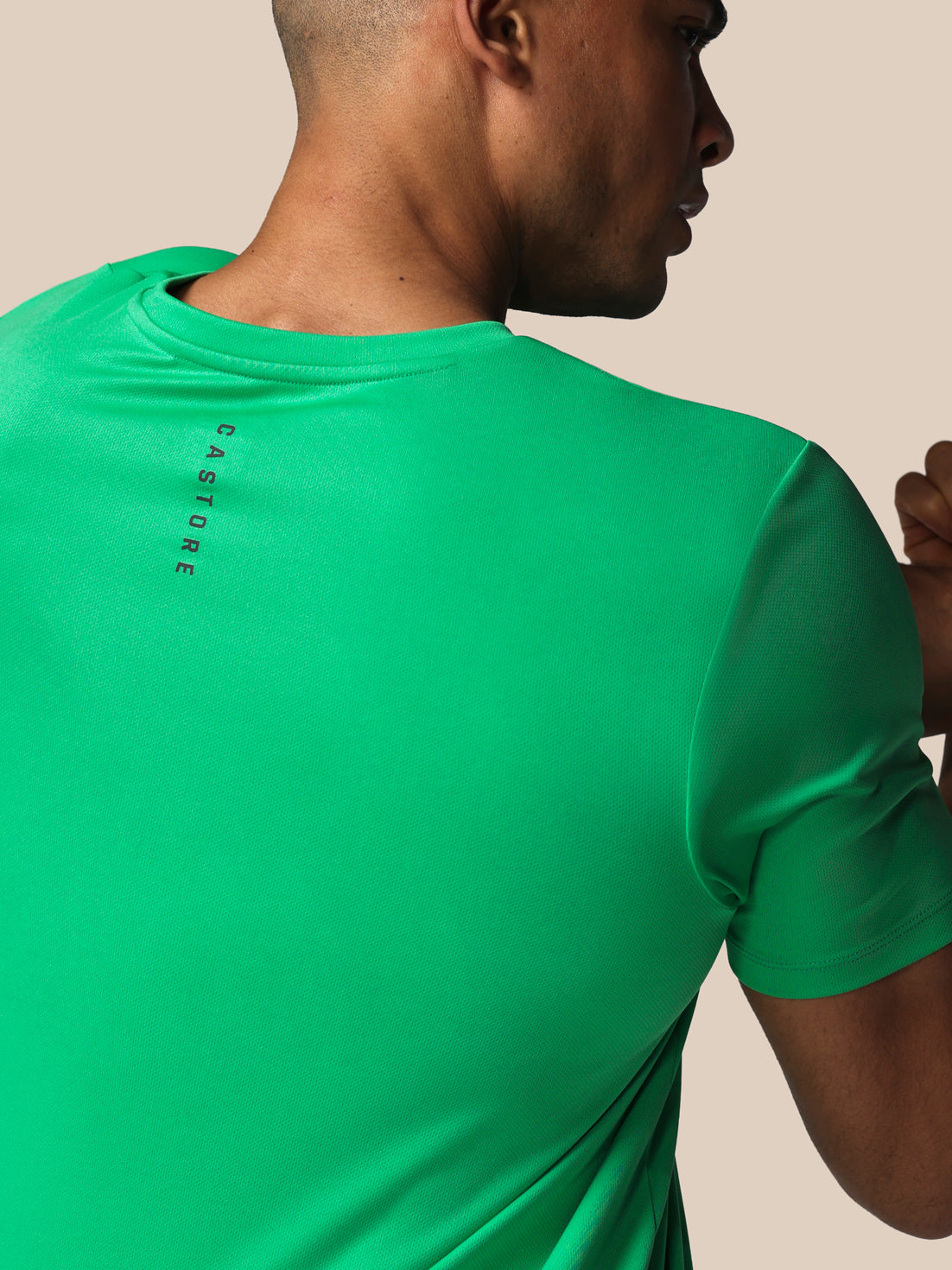 Person wearing a green athletic shirt with 'Castore' branding on the back.