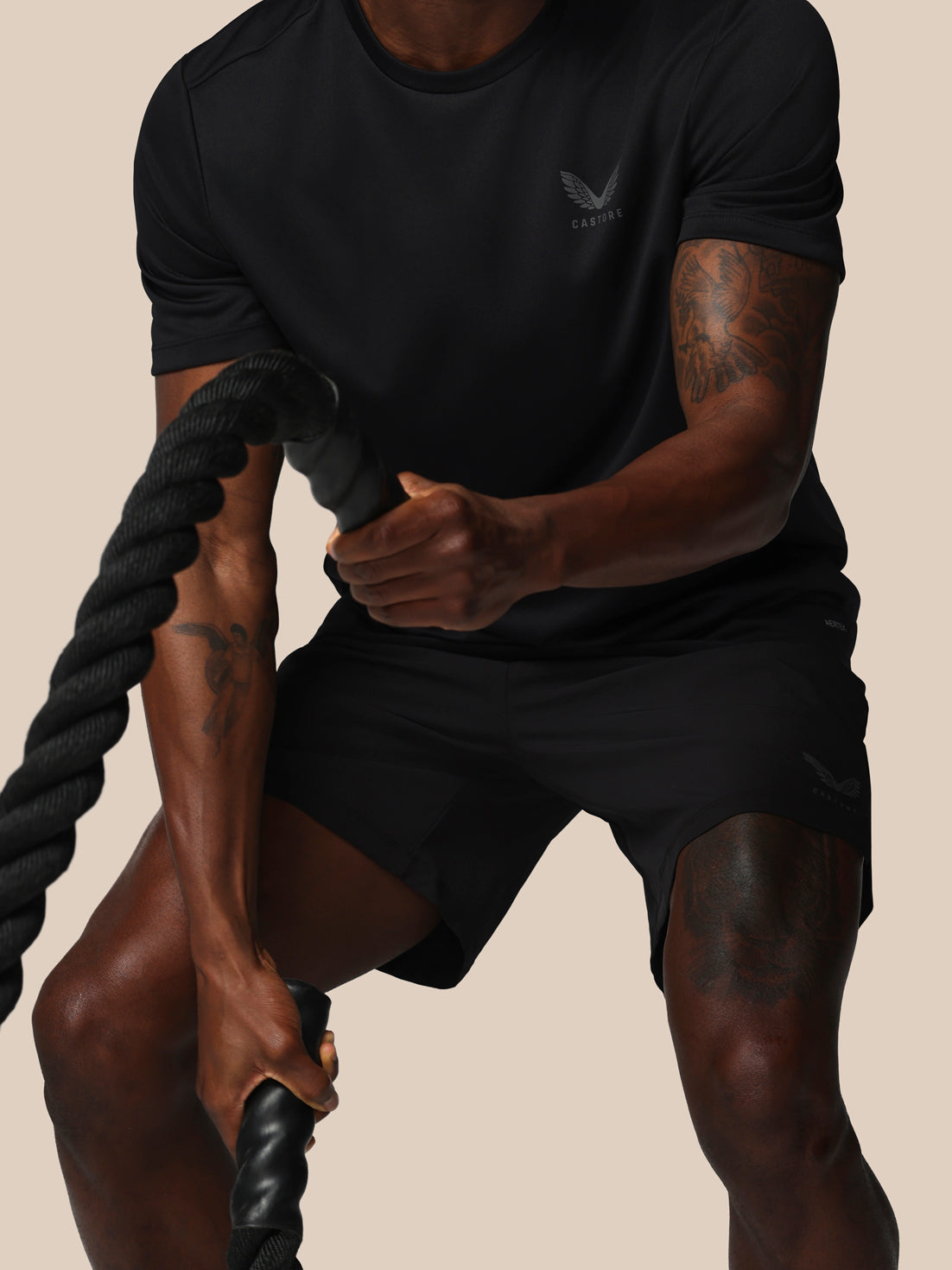 Person holding a rope, wearing a black athletic outfit with a visible brand logo.