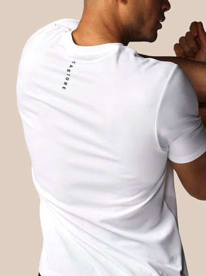 Person wearing a white t-shirt with text on the sleeve against a beige background