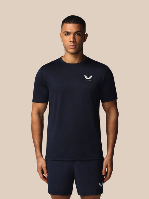 Man wearing a navy blue athletic outfit with a logo on a beige background