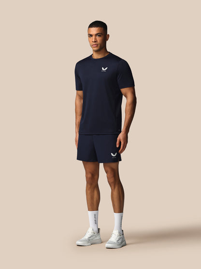 Man wearing a navy athletic outfit with a logo on a beige background