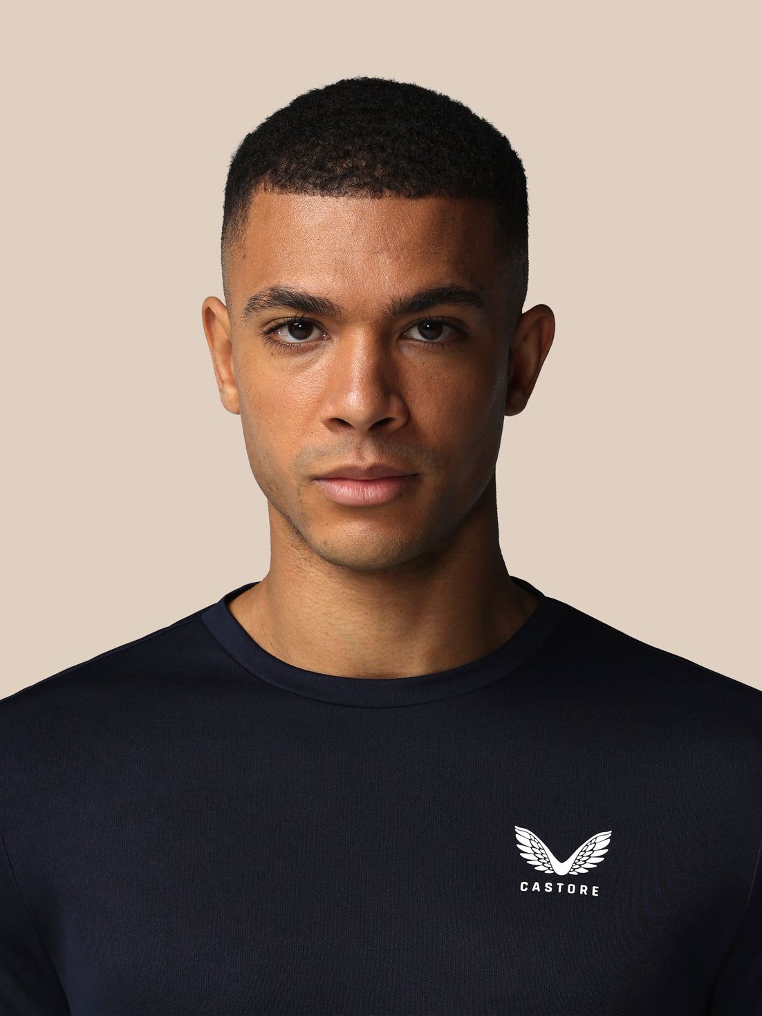 Man wearing a black shirt with a logo on a beige background