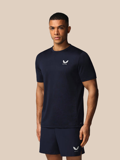 Man wearing a navy blue athletic outfit with a logo on a beige background