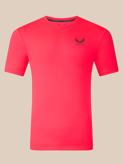 A bright pink short-sleeve athletic t-shirt with a small black winged logo and the brand name 'CASTORE' printed on the left chest, displayed on a solid beige background.