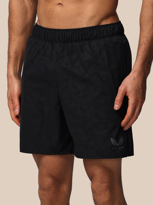 Black athletic shorts with a brand logo on a beige background