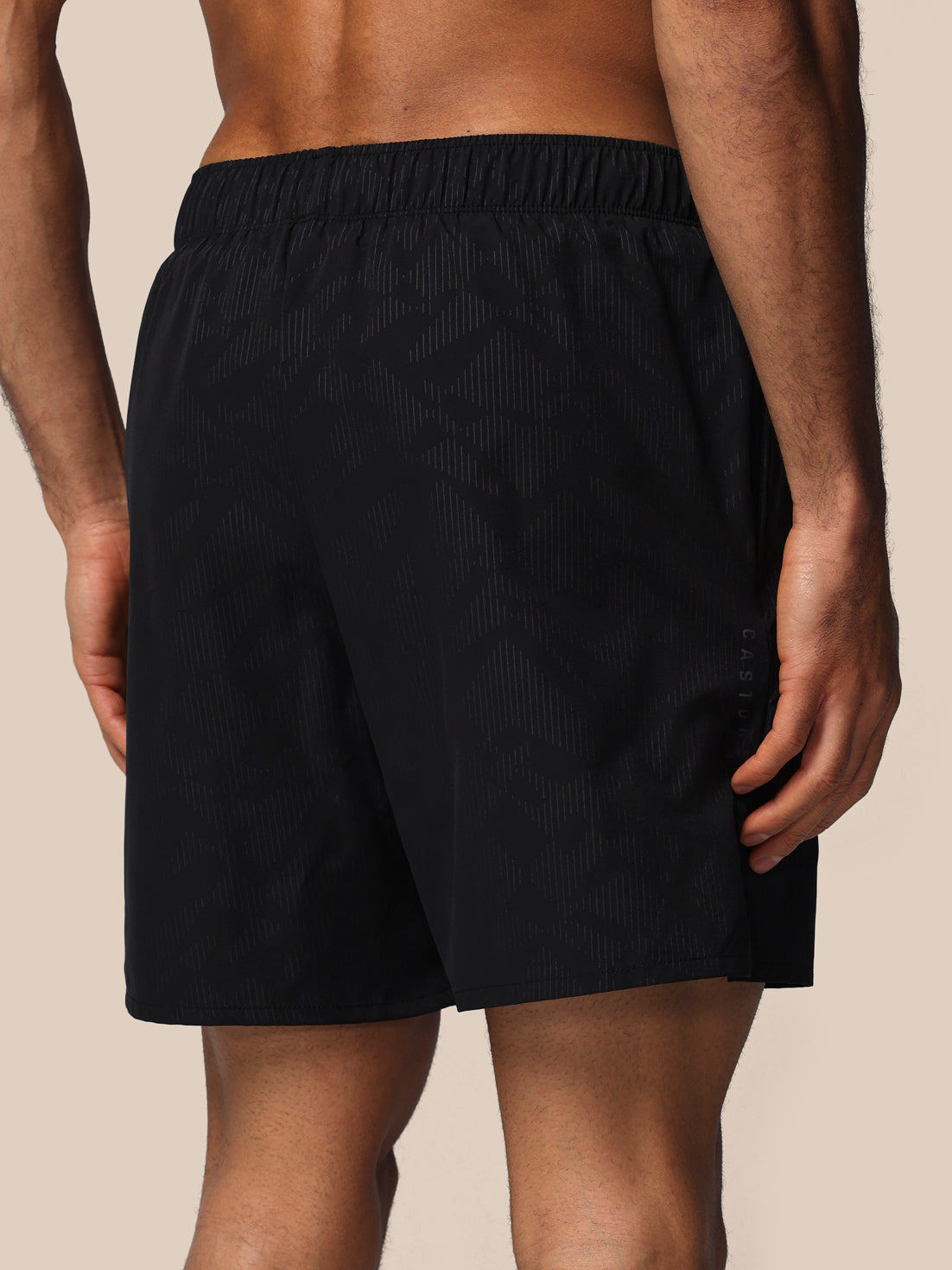 Black shorts worn by a person on a beige background