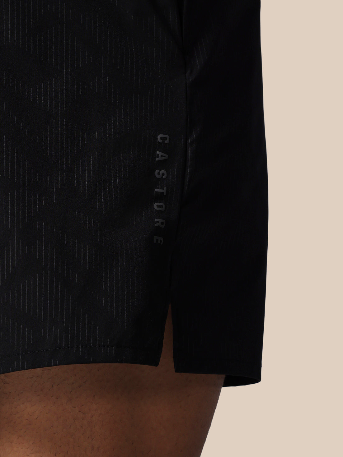 Black athletic shorts with 'CASTORE' branding on a beige background