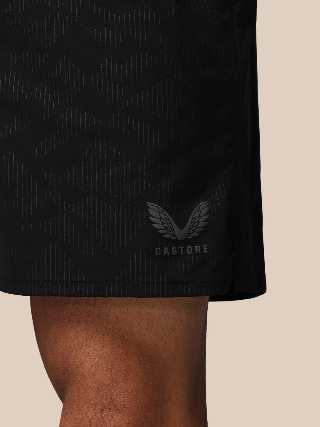 Black athletic shorts with a visible brand logo on a beige background