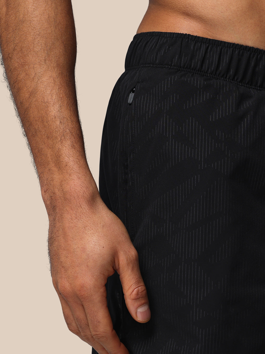 Black athletic shorts worn by a person on a beige background