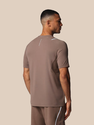 Man wearing a brown athletic outfit with a Castore logo on a beige background