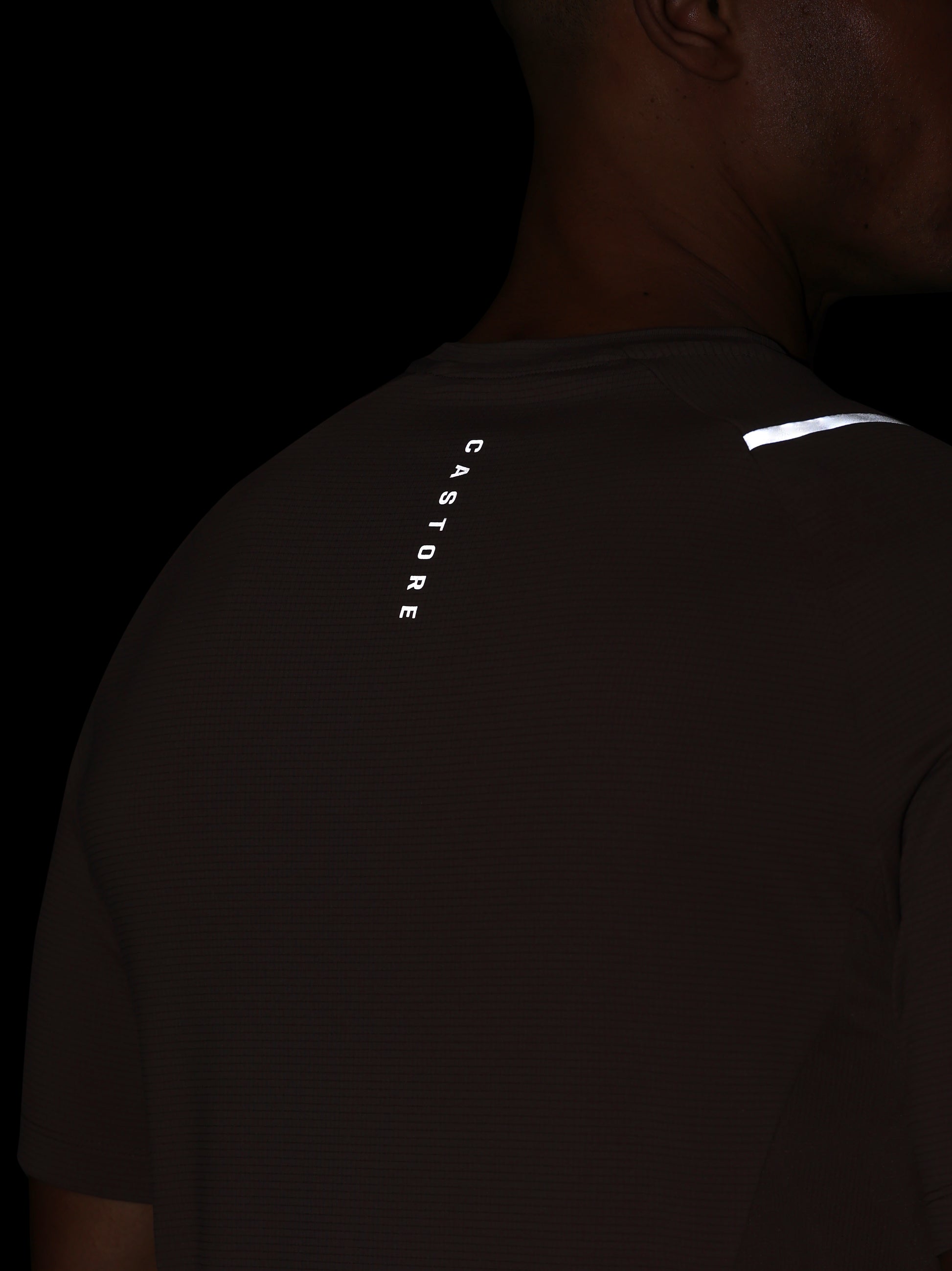 Person wearing a black t-shirt with reflective text and logo on a dark background