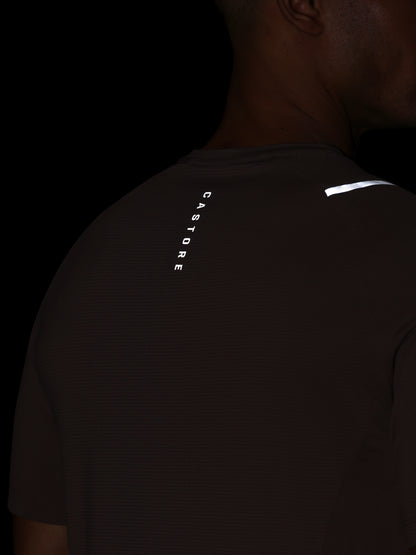 Person wearing a black t-shirt with reflective text and logo on a dark background