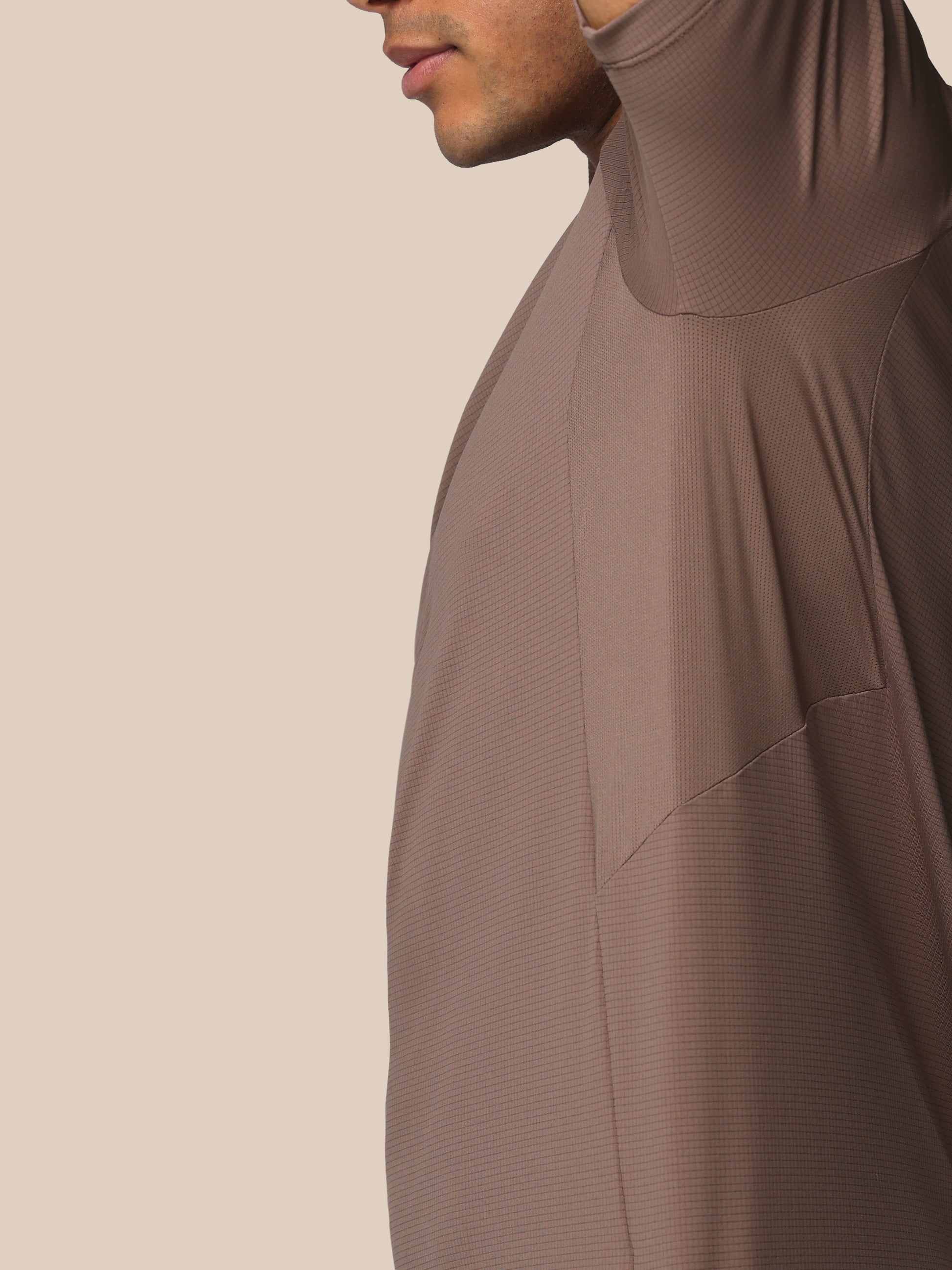 Brown long-sleeve garment worn by a person on a beige background