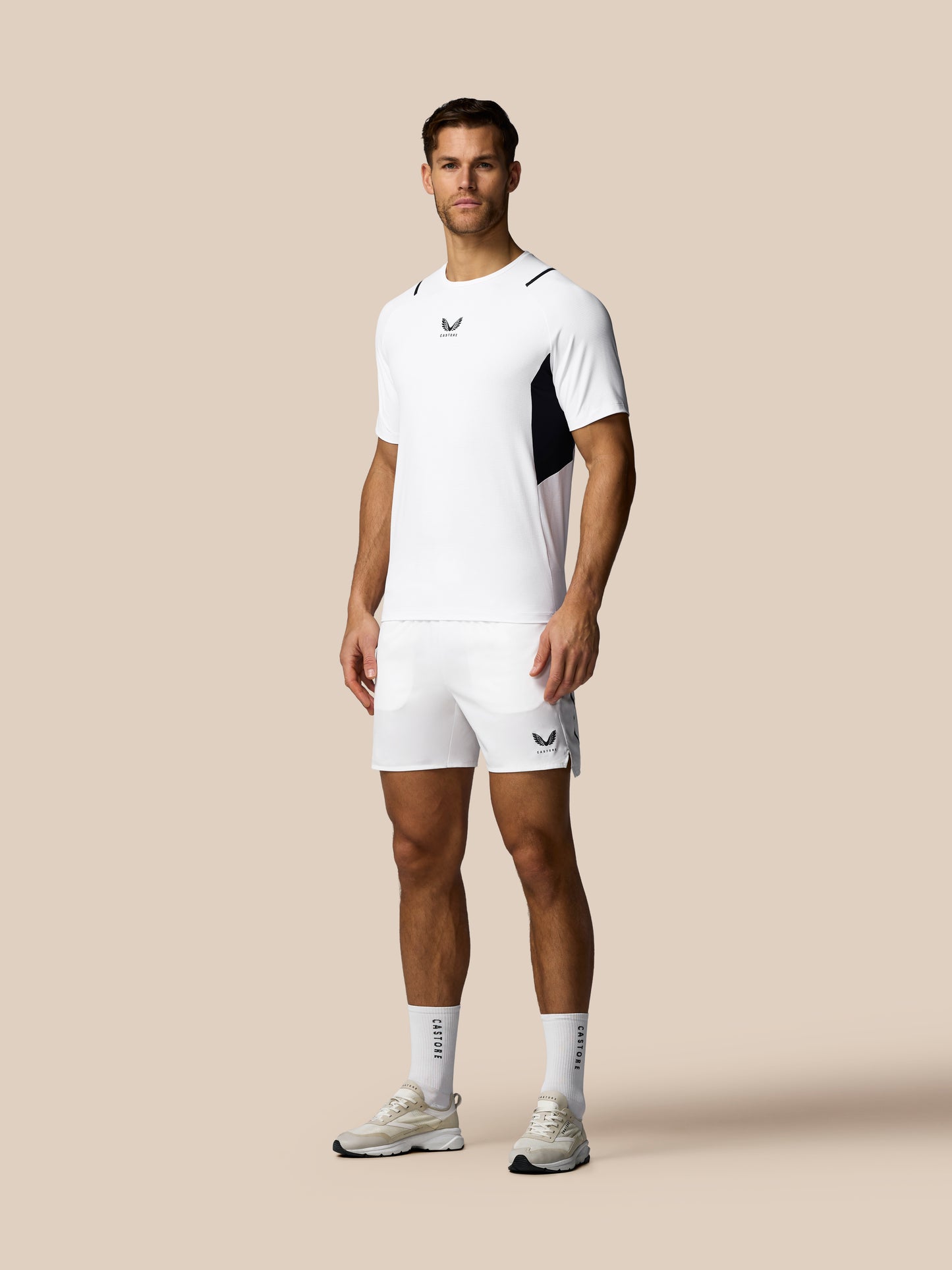 Man wearing a white athletic outfit with black accents on a beige background