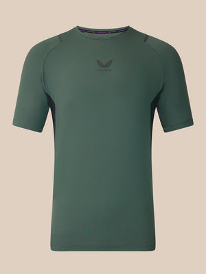 A dark green short-sleeve athletic t-shirt with a subtle winged logo and 'CASTORE' text on the center chest, displayed against a solid beige background.