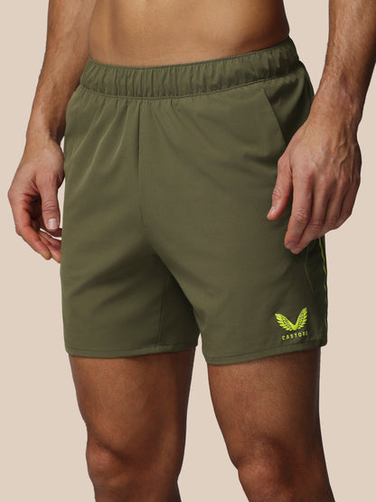 Green athletic shorts with a logo on a beige background