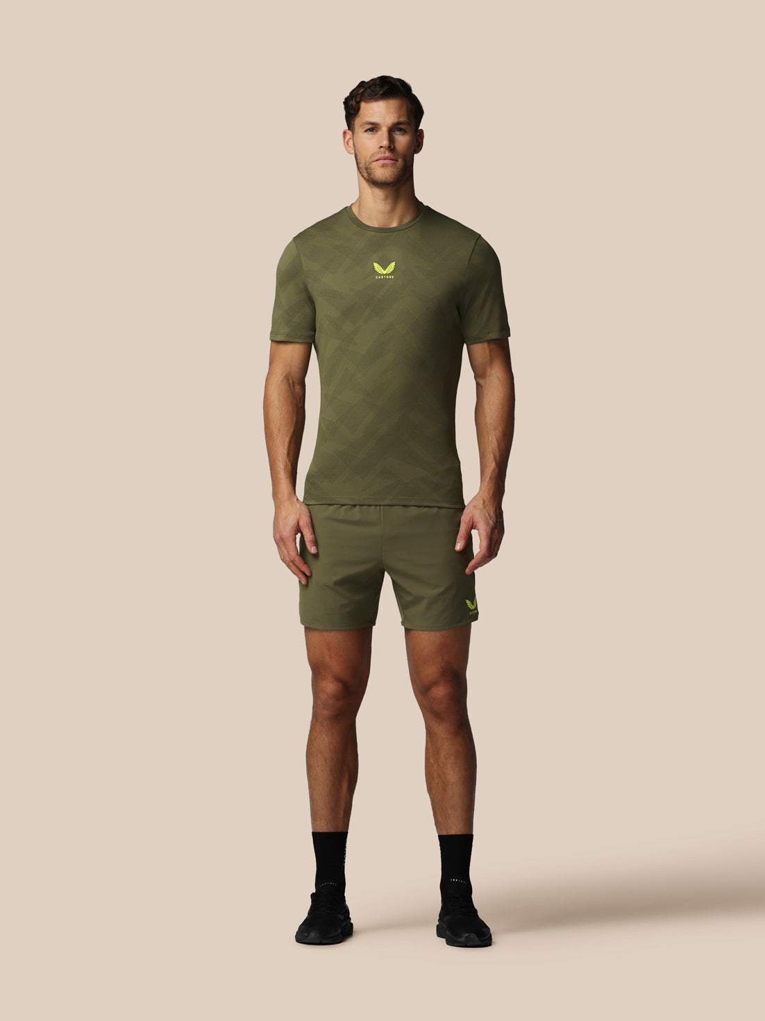 Man wearing a green athletic outfit with a logo on a beige background