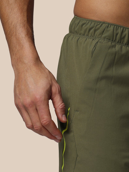 Person wearing green pants with a close-up of the waistband and a hand adjusting it.